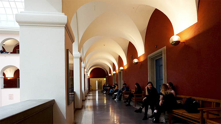 Studierende sitzen in einem Gang im Hauptgebäude der U Z H