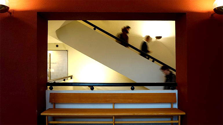 Students walking down a flight of stairs, in front of which a bench is placed