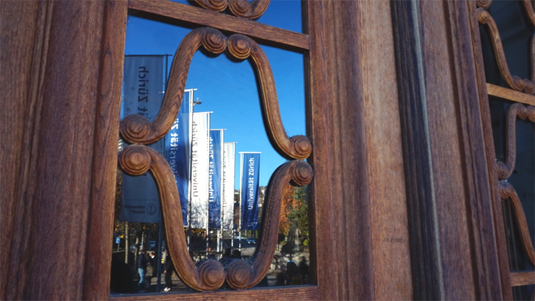 Reflections of U Z H flags in a glass door